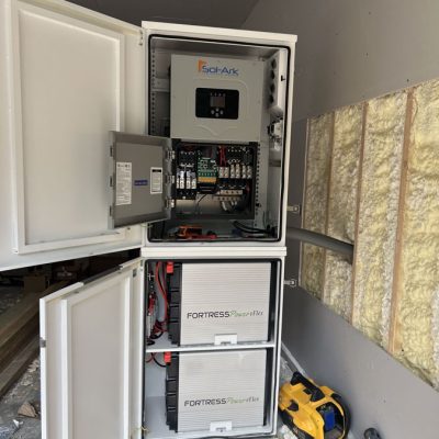 A solar energy storage system with open cabinets displaying batteries and control units, highlighting renewable energy solutions.