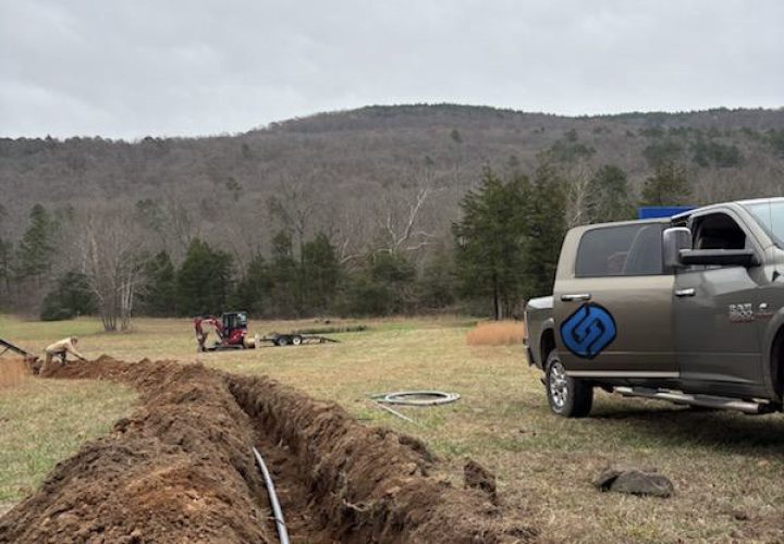 An electrician installing underground electrical lines in a rural setting, highlighting expertise in outdoor and utility-scale electrical projects.