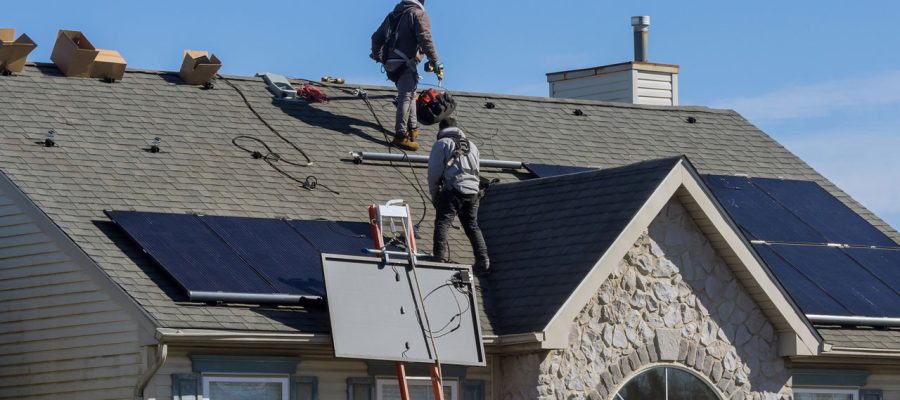 Technicians installing solar panels on the roof of a residential home, promoting sustainable energy solutions.